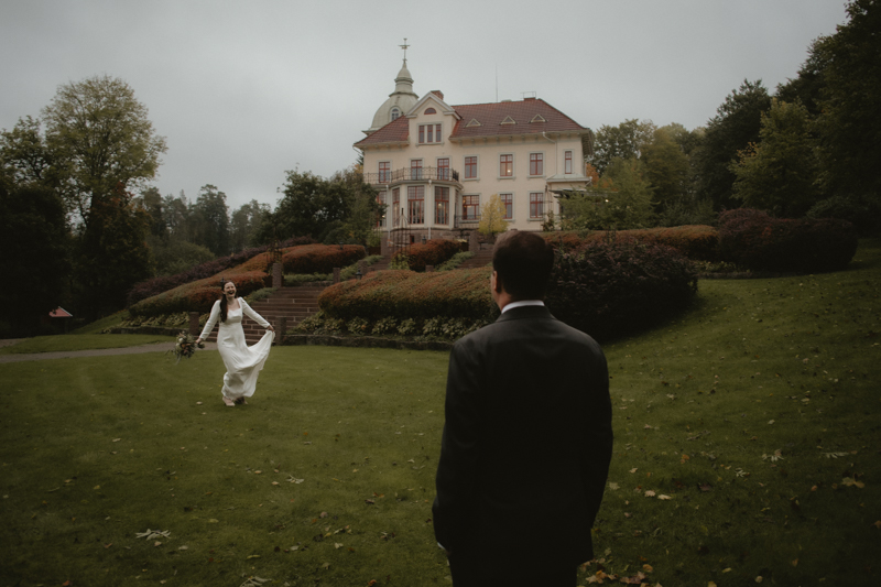 Bruden dansar över gräsmattan framför Villa Strömsfors under stormen Amy, ett lekfullt och romantiskt ögonblick i höstdiset.